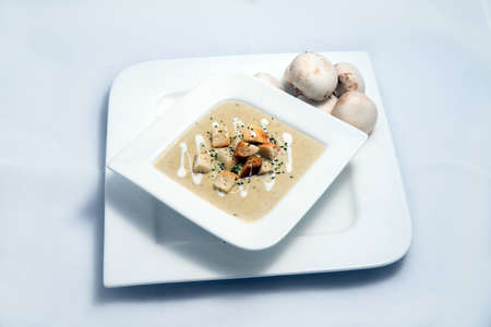 Hero Shot of a Mushroom Soup with bread crumbs, oregano on a minimal white background with a 45 degree angleの写真素材