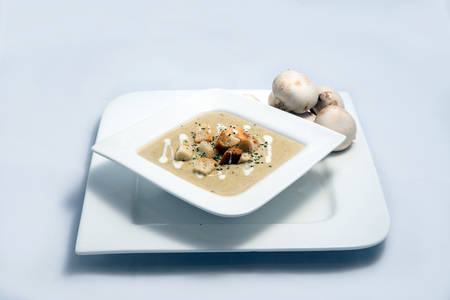 Hero Shot of a Mushroom Soup with bread crumbs, oregano on a minimal white background with a 45 degree angleの写真素材