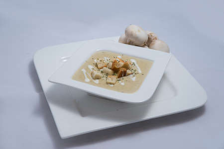 Hero Shot of a Mushroom Soup with bread crumbs, oregano on a minimal white background with a 45 degree angleの写真素材