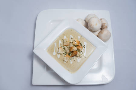 Hero Shot of a Mushroom Soup with bread crumbs, oregano on a minimal white background with a 45 degree angleの写真素材