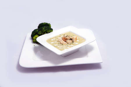 Hero Shot of a Broccoli Soup with bread crumbs, oregano on a minimal white background with a 45 degree front facing angleの写真素材