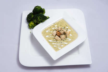 Hero Shot of a Broccoli Soup with bread crumbs, oregano on a minimal white background with a 45 degree front facing angleの写真素材