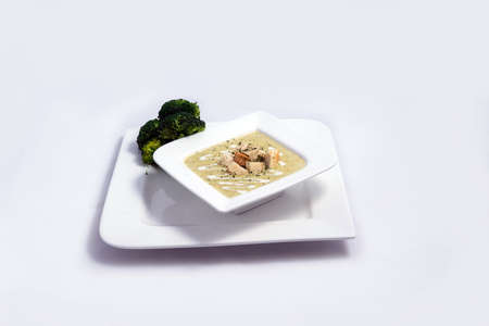 Hero Shot of a Broccoli Soup with bread crumbs, oregano on a minimal white background with a 45 degree front facing angleの写真素材