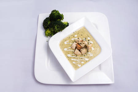Hero Shot of a Broccoli Soup with bread crumbs, oregano on a minimal white background with a 45 degree front facing angleの写真素材