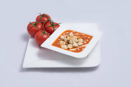 a Hero Shot of a Tomato Soup with bread crumbs, oregano on a minimal white background with a diagonal 45 angleの写真素材