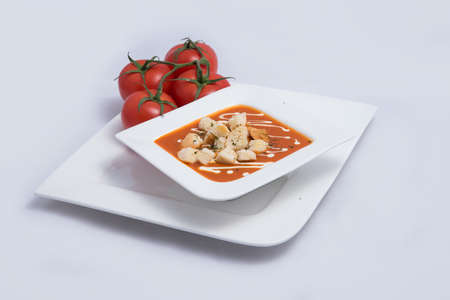 a Hero Shot of a Tomato Soup with bread crumbs, oregano on a minimal white background with a diagonal 45 angleの写真素材