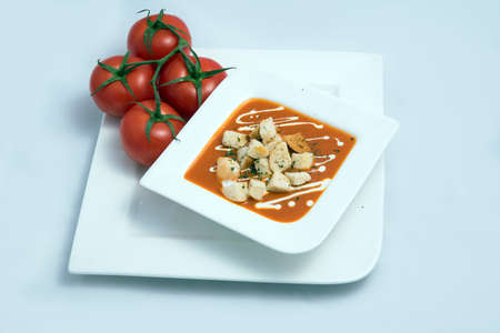 a Hero Shot of a Tomato Soup with bread crumbs, oregano on a minimal white background with a diagonal 45 angleの写真素材