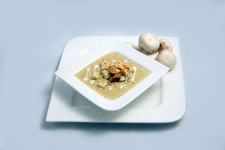 Contrasted Hero Shot of a Mushroom Soup with bread crumbs, oregano on a minimal white background with a 60 degree front facing angleの写真素材