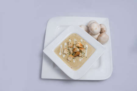 Contrasted Hero Shot of a Mushroom Soup with bread crumbs, oregano on a minimal white background with a 60 degree front facing angleの写真素材