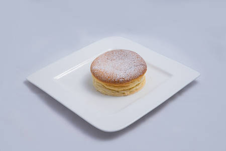 A low contrast Hero Shot of a pan cake on a plate, on a minimal white background with a diagonal 60 degree angleの写真素材