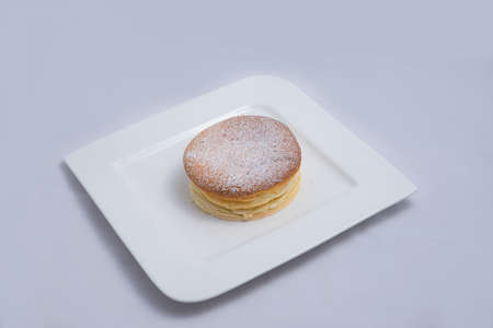 A low contrast Hero Shot of a pan cake on a plate, on a minimal white background with a diagonal 60 degree angleの写真素材