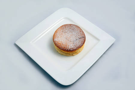 A low contrast Hero Shot of a pan cake on a plate, on a minimal white background with a diagonal 60 degree angleの写真素材