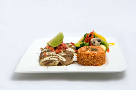 A Hero shot of a grilled fish fillet gratini with vegetables & lentils on the side, on a white plate, minimal background with a 60 degree front facing perspective.の写真素材