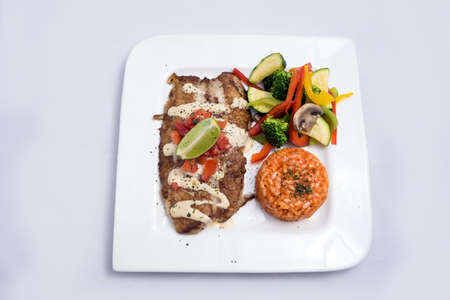 A Hero shot of a grilled fish fillet gratini with vegetables & lentils on the side, on a white plate, minimal background with a 60 degree front facing perspective.の写真素材