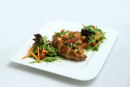 A low contrast Hero shot of a breakfast platter with vegetable-filled croissant with vegetables- carrot, tomato, lettuce on a minimal white background with a 30 degree angle from diagonal perspective.の写真素材