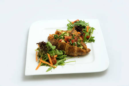 A low contrast Hero shot of a breakfast platter with vegetable-filled croissant with vegetables- carrot, tomato, lettuce on a minimal white background with a 30 degree angle from diagonal perspective.の写真素材