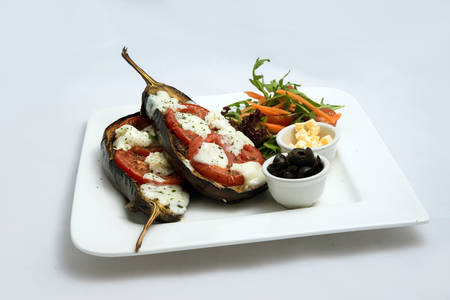 A low contrast warm Hero shot of a main course platter with grilled aubergine with buffalo cheese, tomato, olives & vegetables on the side, on a minimal white background with a 45 degree angle from diagonal perspective.の写真素材
