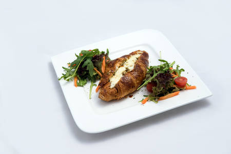 A low contrast Hero shot of a breakfast platter with cheese and zaatar filled croissant with vegetables- carrot, tomato, lettuce on a minimal white background with a 30 degree angle from front perspectiveの写真素材