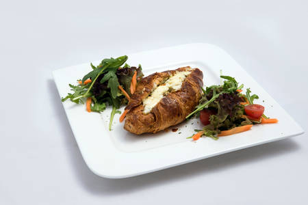 A low contrast Hero shot of a breakfast platter with cheese and zaatar filled croissant with vegetables- carrot, tomato, lettuce on a minimal white background with a 30 degree angle from front perspectiveの写真素材