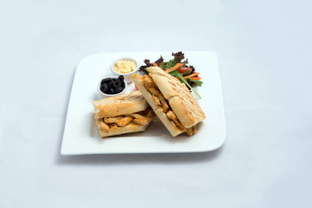 A low contrast Hero shot of a breakfast platter with grilled chicken panini sandwich with olives, cheese & vegetables- carrot, tomato, lettuce on a minimal white background with a 45 degree angle from almost front perspectiveの写真素材