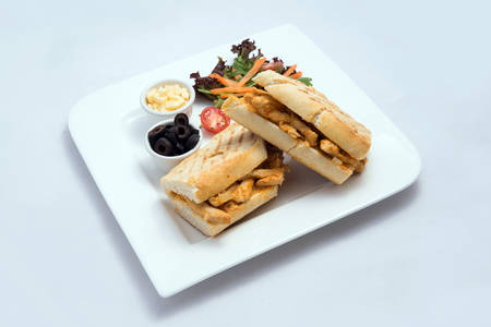 A low contrast Hero shot of a breakfast platter with grilled chicken panini sandwich with olives, cheese & vegetables- carrot, tomato, lettuce on a minimal white background with a 45 degree angle from almost front perspectiveの写真素材