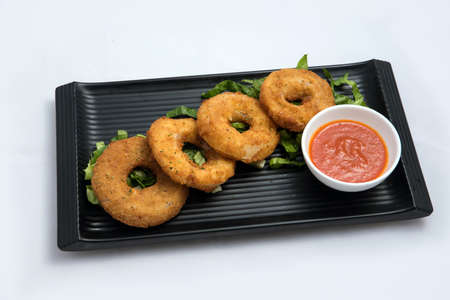 A low contrast Hero shot of an appetizer platter of onion rings with lettuce and tomato chutney on a minimal white background with a 45 degree angle front perspectiveの写真素材