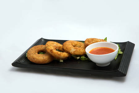A low contrast Hero shot of an appetizer platter of onion rings with lettuce and tomato chutney on a minimal white background with a 45 degree angle front perspectiveの写真素材