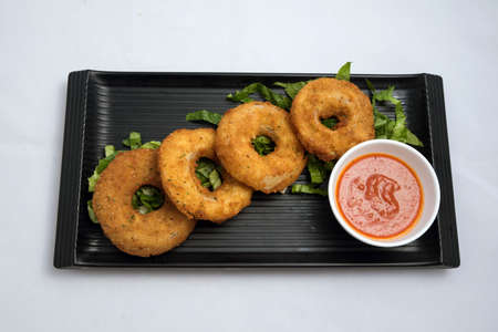 A low contrast Hero shot of an appetizer platter of onion rings with lettuce and tomato chutney on a minimal white background with a 45 degree angle front perspectiveの写真素材