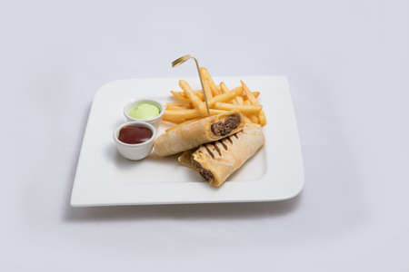 A low contrast Hero shot of a beef wrap sandwich with samurai & alger sauce and fries on the side, on a minimal white background with a 45 degree angle from front zoomed in perspectiveの写真素材