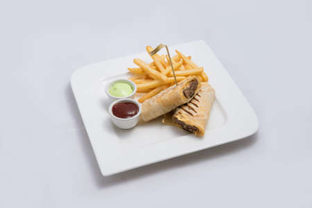 A low contrast Hero shot of a beef wrap sandwich with samurai & alger sauce and fries on the side, on a minimal white background with a 45 degree angle from front zoomed in perspectiveの写真素材