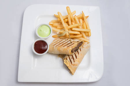 A low contrast Hero shot of a beef wrap sandwich with samurai & alger sauce and fries on the side, on a minimal white background with a 45 degree angle from front zoomed in perspectiveの写真素材