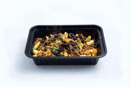 A high contrast Hero shot of a Take-Away Hot Loaded fries / chips with ground meat, olives, cheese, jalapeno, sauce & oregano., on a minimal white background with a 45 degree angle from zoomed out frontal perspective.の写真素材