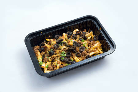 A high contrast Hero shot of a Take-Away Hot Loaded fries / chips with ground meat, olives, cheese, jalapeno, sauce & oregano, on a minimal white background with a 60 degree angle from zoomed out right diagonal perspective.の写真素材