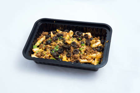 A high contrast Hero shot of a Take-Away Hot Loaded fries / chips with ground meat, olives, cheese, jalapeno, sauce & oregano, on a minimal white background with a 60 degree angle from zoomed out left diagonal perspective.の写真素材