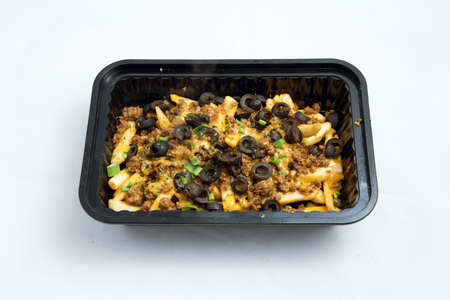 A high contrast Hero shot of a Take-Away Hot Loaded fries / chips with ground meat, olives, cheese, jalapeno, sauce & oregano, on a minimal white background with a 75 degree angle from zoomed out vertical perspective.の写真素材