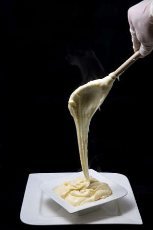 A high contrast artistic hero shot of fresh hot cheese served on to a platter with smoke coming off the stretched cheese on a minimal white background from a flat horizontal perspectiveの写真素材