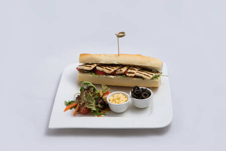 A low contrast Hero shot of a Grilled Halloumi cheese baguette with olives & salad on the side, on a minimal white background with a 45 degree angle from frontal zoomed perspectiveの写真素材