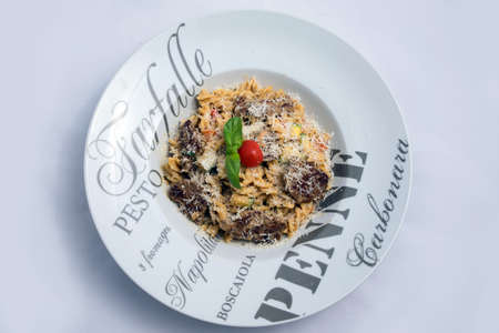 A high contrast Hero shot of a Tuna pasta /  tuna tapenade with olives, tomato & salad, on a minimal white background with a 45 degree angle from zoomed frontal perspectiveの写真素材