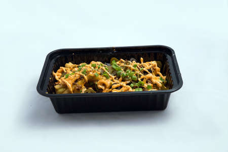 A high contrast Hero shot of a Take-Away Hot Loaded fries / chips with cheese, ground meat, olives, jalapeno, sauce & oregano, on a minimal white background with a 45 degree angle from zoomed out frontal perspective.の写真素材