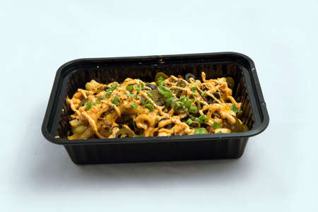 A high contrast Hero shot of a Take-Away Hot Loaded fries / chips with cheese, ground meat, olives, jalapeno, sauce & oregano, on a minimal white background with a 45 degree angle from zoomed out frontal perspective.の写真素材