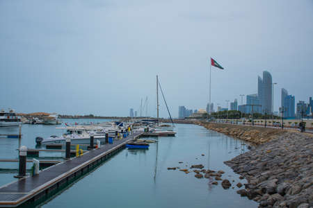 Motorboats & yachts parked at the Abu Dhabi Marina on a rainy day with the Abu Dhabi skyline at the...