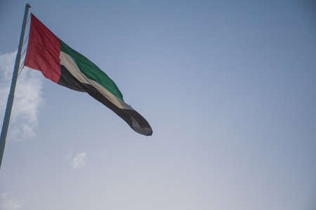 United Arab Emirates flag waving at full mast against a blue skyの写真素材