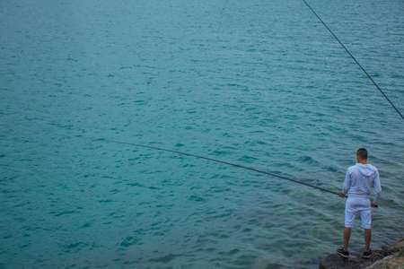 a man pulls at a fishing rod in the sea to catch fish on a rainy weekendのeditorial素材