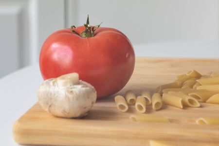 Ingredients for tradional italian pasta dish: dry penne, tomatoes, basil, mushrooms and garlic