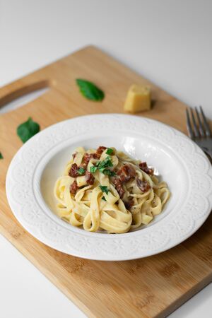 Traditional Italian pasta fettuccine alfredo with sun-dried tomatoes and basil made vegan. Sauce made with bechamel, plant-based milk, olive oil and garlic.の写真素材