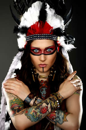 Beautiful woman in native american costume with roach on her head posing in a studioの写真素材