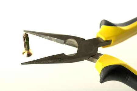 Black and yellow pliers and screw over whiteの写真素材