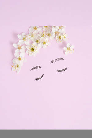 Bright creative drawing spring design.  A woman with her eyes closed with her hair made of tiny cherry blossoms on a pastel purple background. Flat lay minimal concept.の写真素材