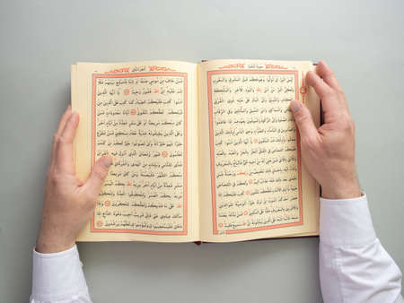 A man recites the holy Quran, verses about Ramadan fasting. Flat lay creative Ramadan Kareem...