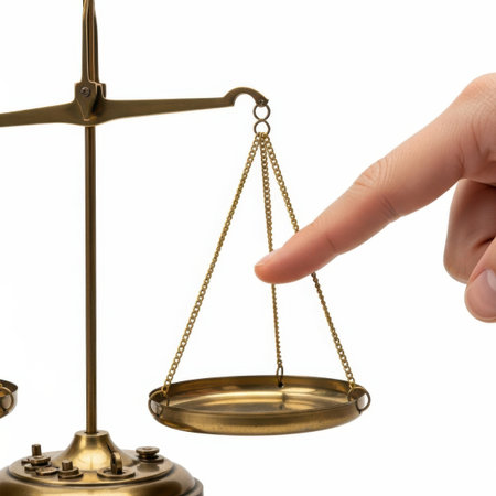 A close-up of a hand delicately touching a brass balance scale, emphasizing balance and fairness, isolated on a white background.の写真素材